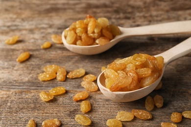 Spoons with raisins on wooden table. Dried fruit as healthy snack