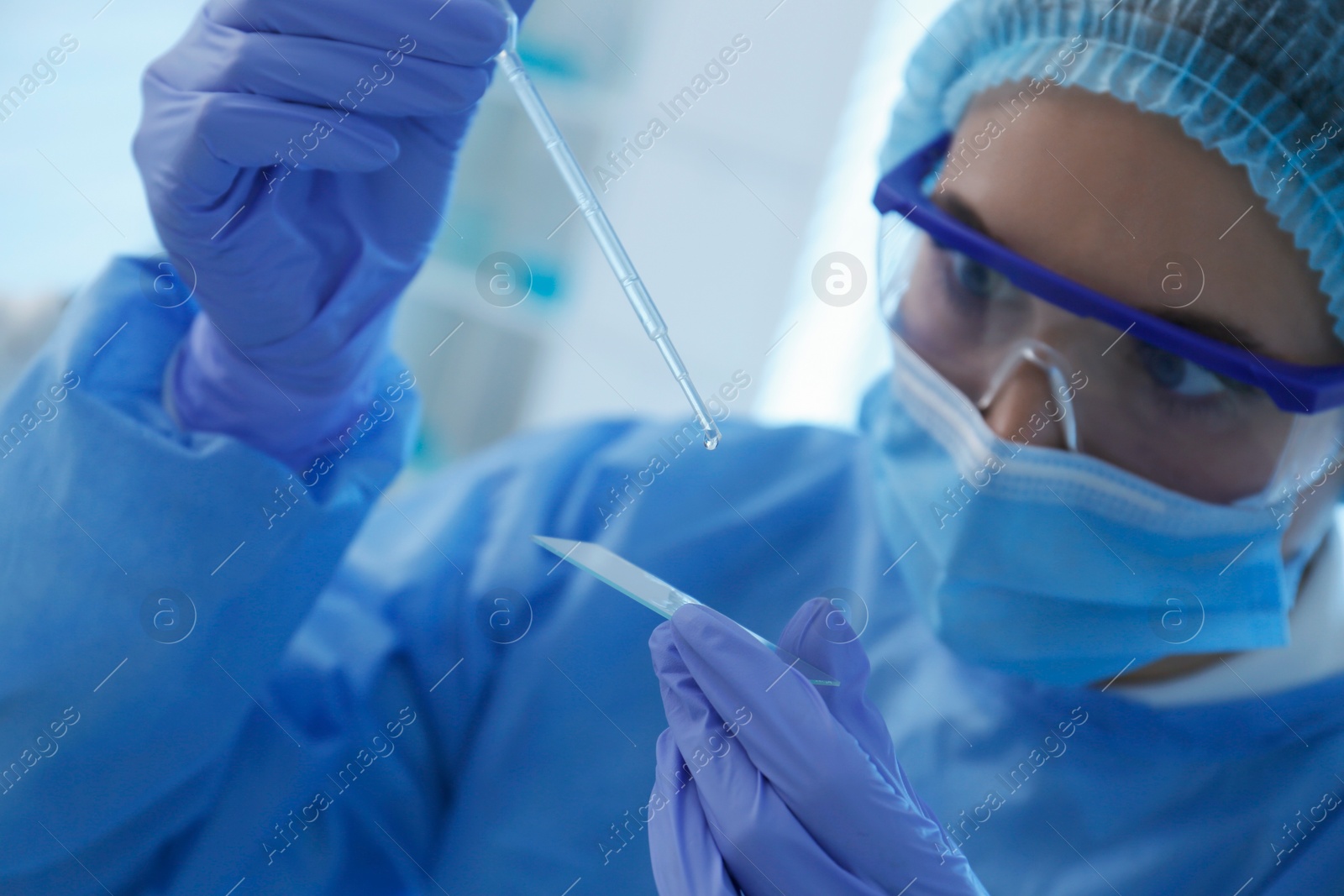 Photo of Scientist dripping sample onto glass slide in laboratory, focus on hands. Medical research