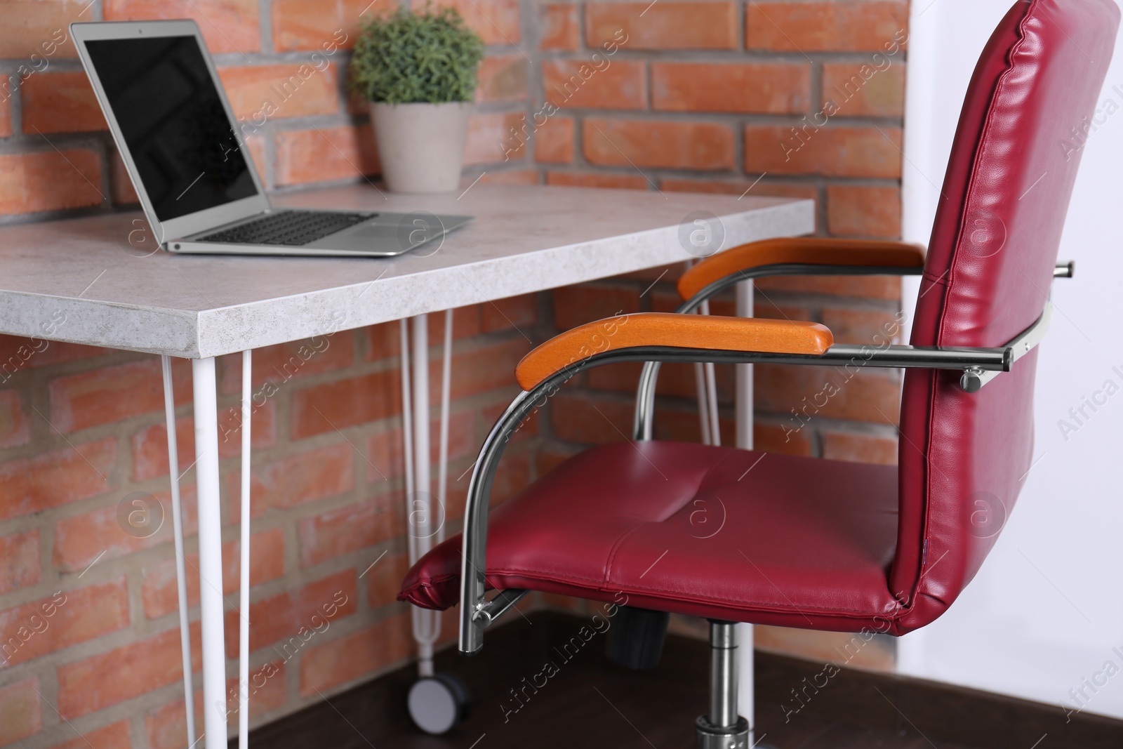 Photo of Comfortable red desk chair near table with laptop in modern office