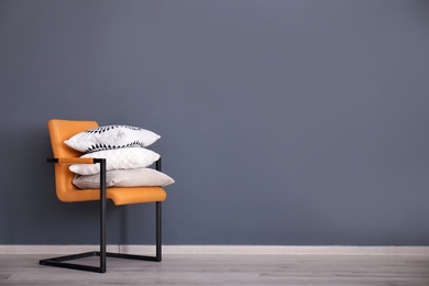 Photo of Stack of pillows on armchair near grey wall