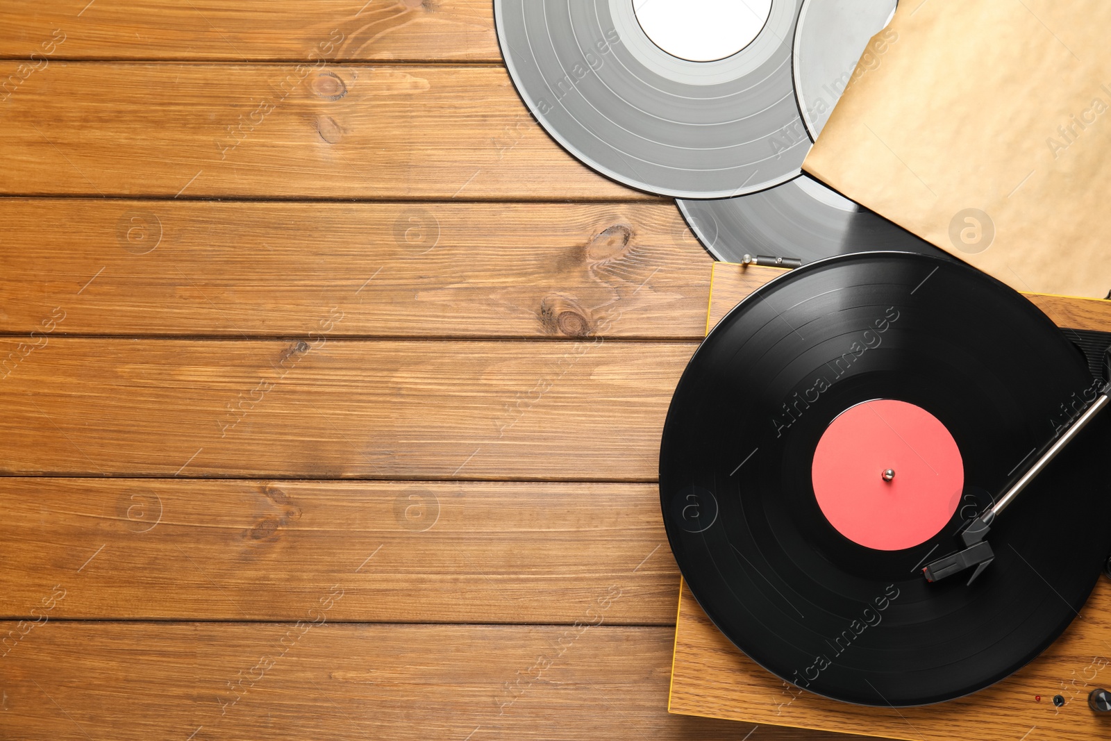 Photo of Vintage vinyl records and turntable on wooden background, flat lay. Space for text