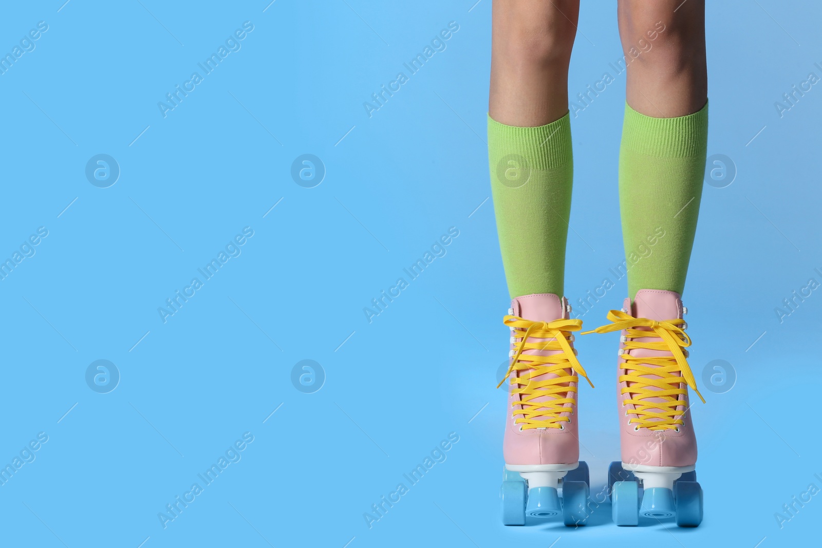 Photo of Woman with vintage roller skates on color background, closeup. Space for text