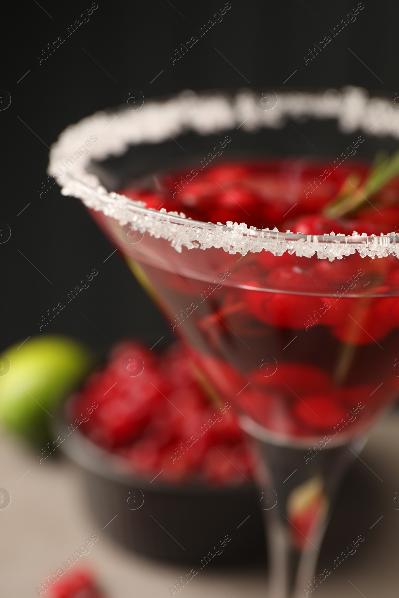 Photo of Tasty cranberry cocktail with rosemary in glass against black background, closeup