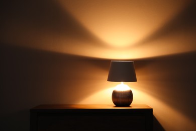 Photo of Stylish glowing  night lamp on table in room. Space for text