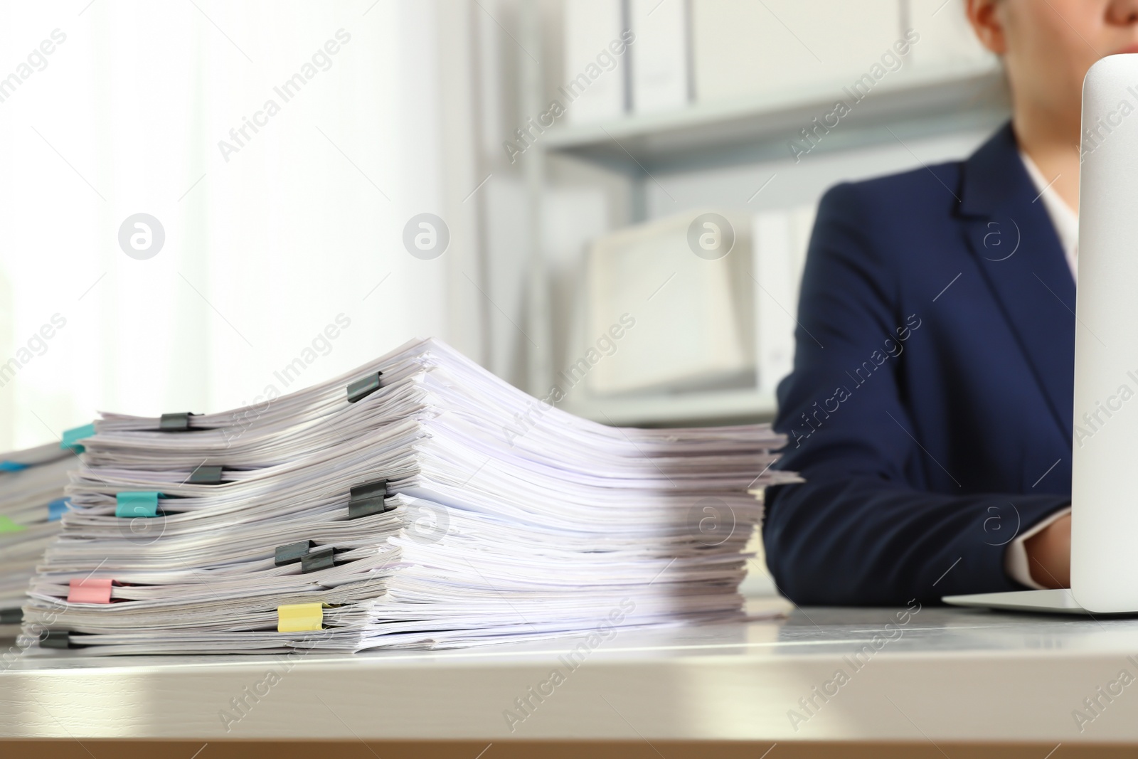 Photo of Female worker working with laptop near stack of documents in office, closeup