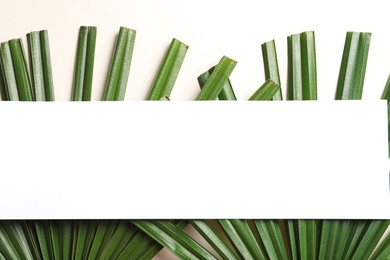 Photo of Creative composition with tropical leaves and card on light background, top view
