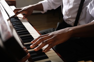 African-American man playing piano indoors, closeup. Talented musician