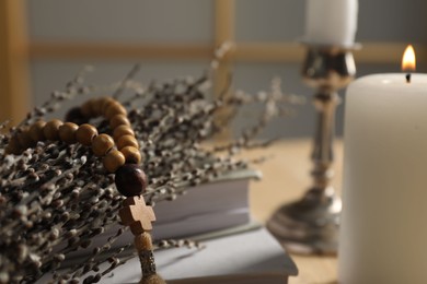 Photo of Rosary beads and willow branches on table, closeup. Space for text