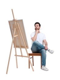 Man with brush painting against white background. Using easel to hold canvas