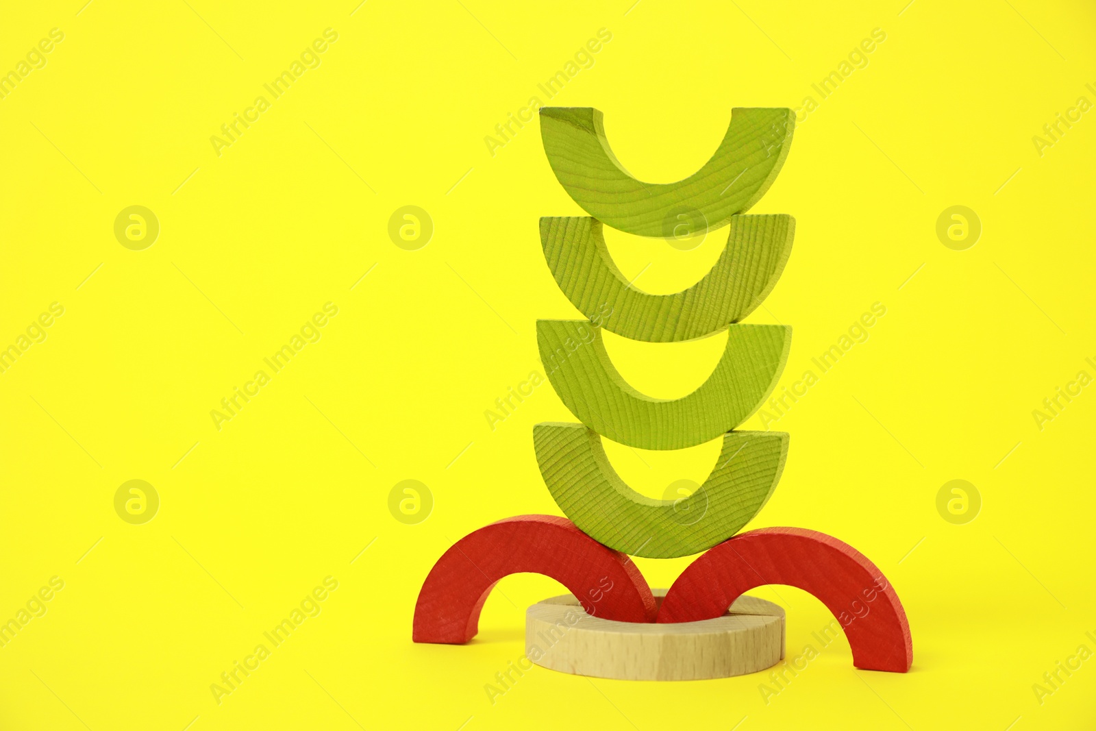 Photo of Colorful wooden pieces of playing set on yellow background, space for text. Educational toy for motor skills development