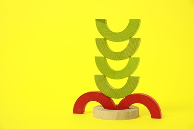 Photo of Colorful wooden pieces of playing set on yellow background, space for text. Educational toy for motor skills development