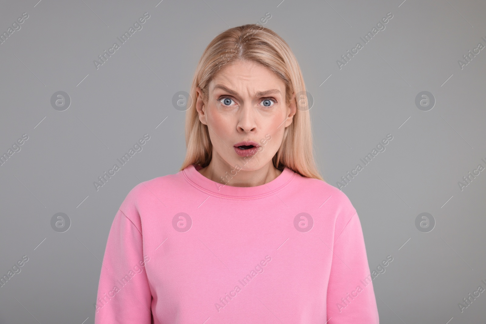 Photo of Portrait of surprised woman on grey background