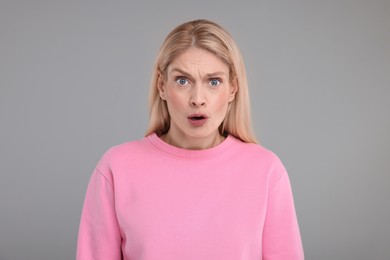 Portrait of surprised woman on grey background