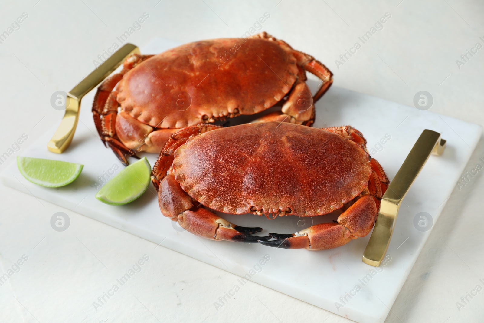 Photo of Delicious boiled crabs and lime on white table