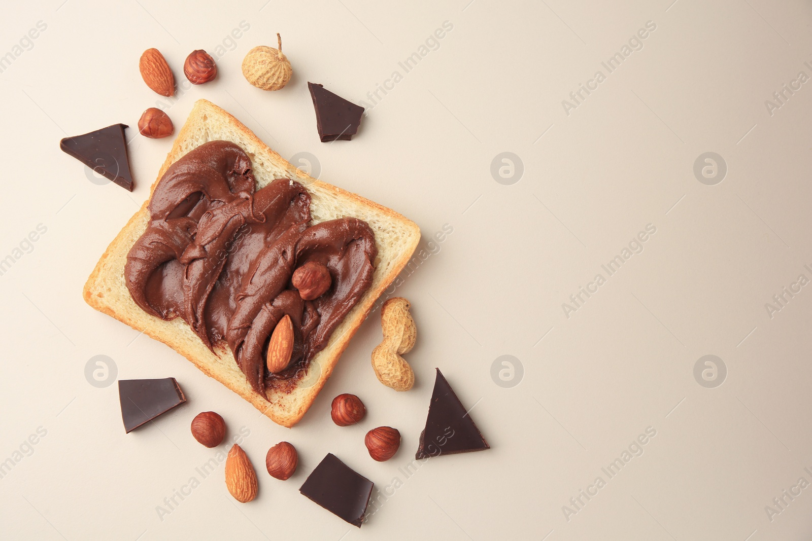 Photo of Tasty toast with chocolate paste and nuts on beige background, flat lay. Space for text