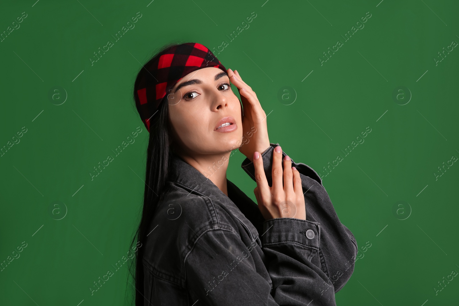 Photo of Fashionable young woman in stylish outfit with bandana on green background