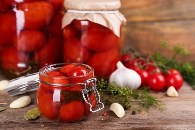 Photo of Glass jar of pickled cherry tomatoes on wooden table. Space for text