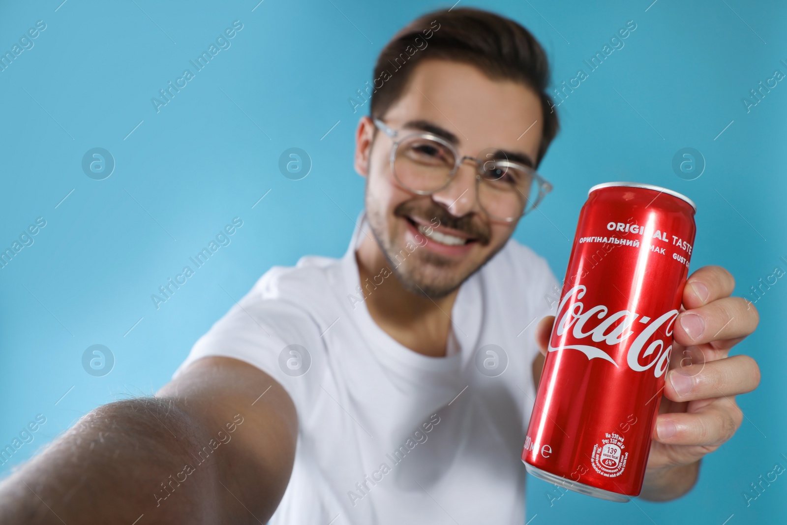 Photo of MYKOLAIV, UKRAINE - NOVEMBER 28, 2018: Young man taking selfie with Coca-Cola can on color background