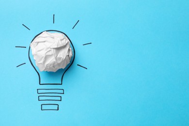 Photo of Idea concept. Light bulb made with crumpled paper and drawing on light blue background, top view. Space for text