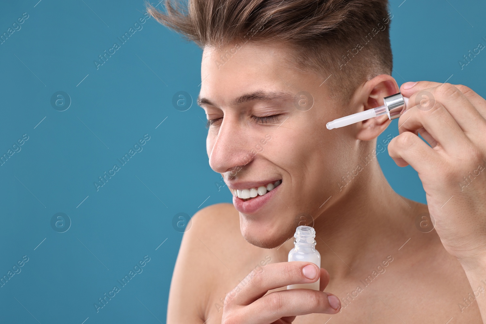 Photo of Handsome man applying serum onto his face on blue background, closeup. Space for text