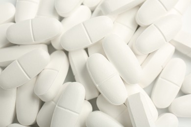 Photo of White vitamin capsules as background, top view