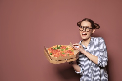 Photo of Attractive young woman with delicious pizza on color background