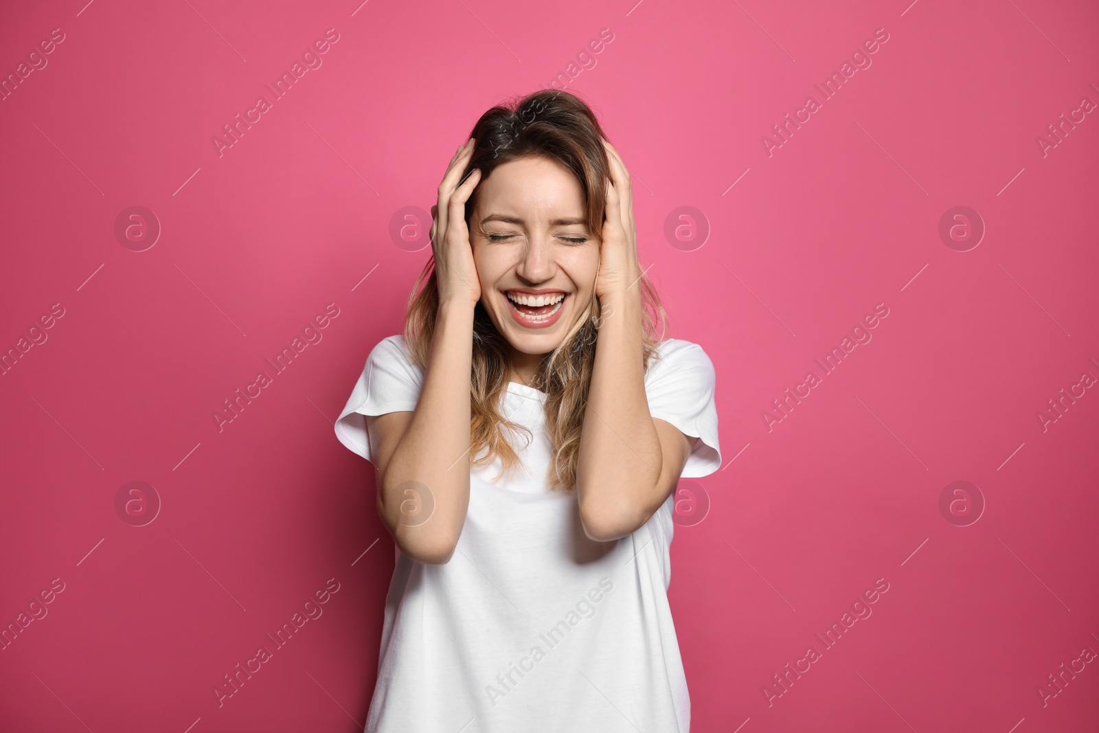 Photo of Cheerful young woman laughing on pink background