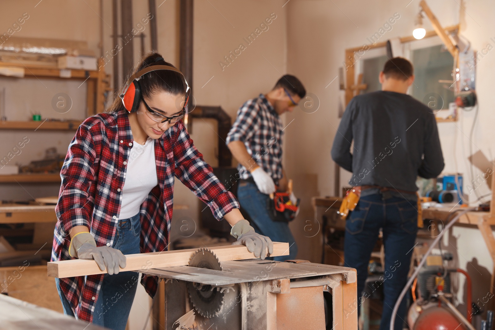 Photo of Professional carpenter working with sawmill machine near colleagues in workshop