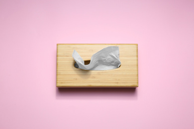 Photo of Wooden holder with paper tissues on pink background, top view