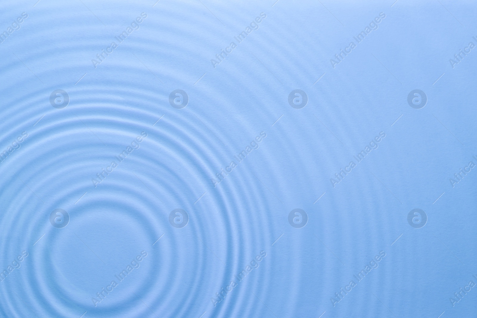 Image of Rippled surface of clear water on light blue background, top view