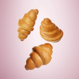 Golden croissants falling on pink gradient background