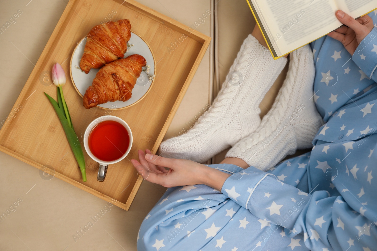 Photo of Woman with cup of tea and book resting on sofa, top view