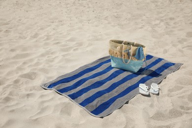 Beach towel with bag, flip flops and swimsuit on sand