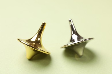Photo of Golden and silver spinning tops on green background, closeup