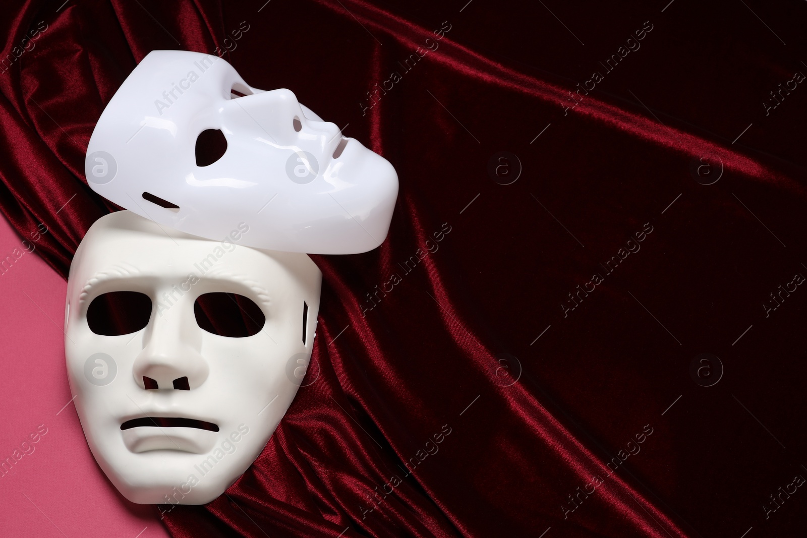 Photo of Theater arts. White masks and red fabric on pink background, space for text