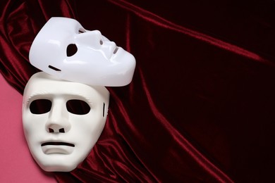 Photo of Theater arts. White masks and red fabric on pink background, space for text