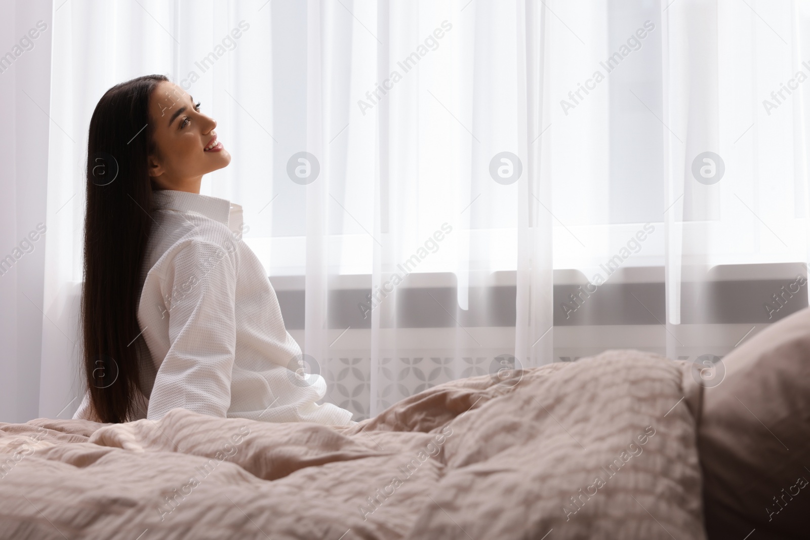 Photo of Beautiful woman sitting on bed at home, space for text. Lazy morning