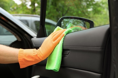 Photo of Man washing car door from inside with rag, closeup