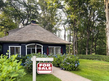 Red sign with words For Sale near beautiful house outdoors