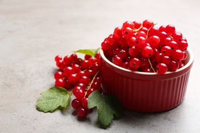 Photo of Delicious red currants and leaves on light grey table