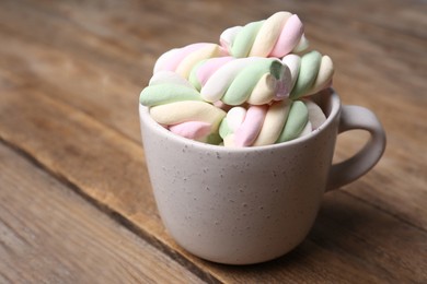 Photo of Ceramic cup with colorful marshmallows on wooden table, closeup