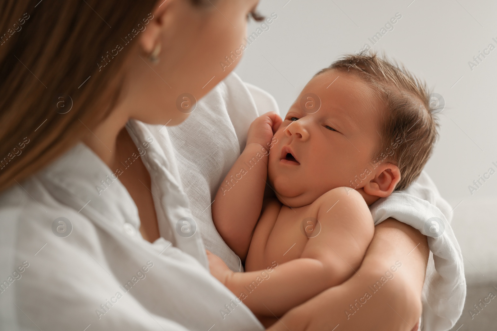 Photo of Mother holding her cute newborn baby on light grey background, closeup