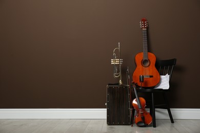 Photo of Set of different musical instruments near brown wall indoors, space for text