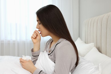 Sick young woman with tissue in bed at home