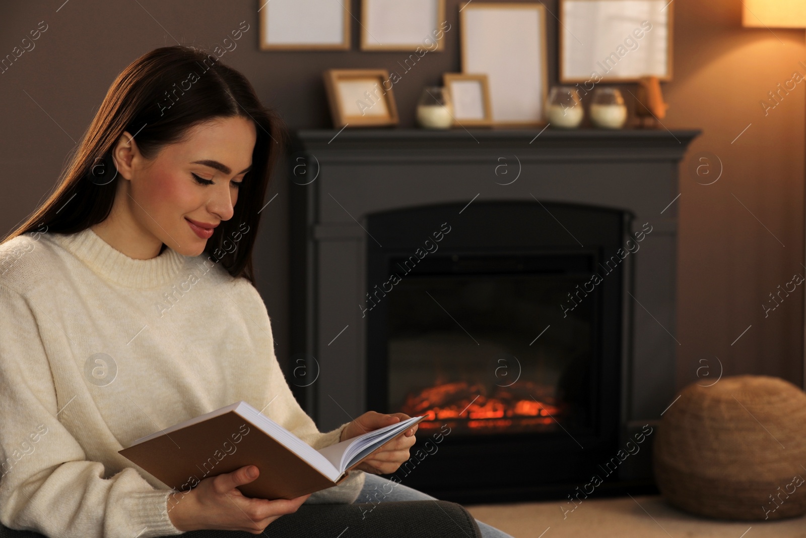Photo of Beautiful young woman reading book at home. Space for text
