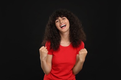 Happy sports fan celebrating on black background