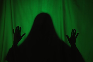 Photo of Silhouette of creepy ghost behind dark green cloth