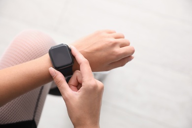 Image of Woman using stylish smart watch indoors, top view