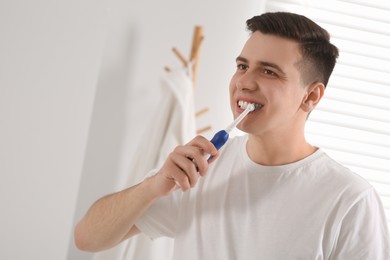 Man brushing his teeth with electric toothbrush in bathroom