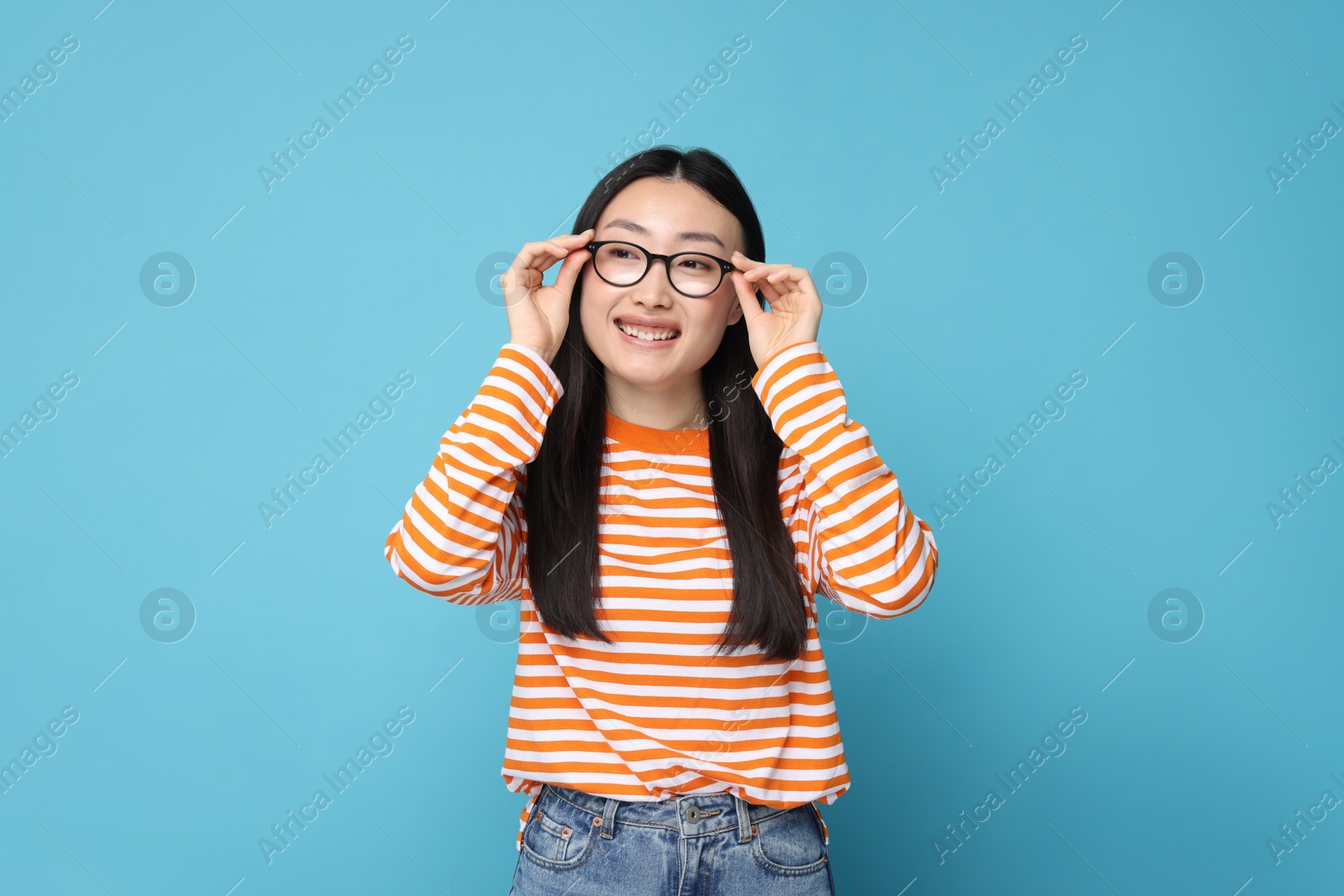 Photo of Portrait of happy woman in glasses on light blue background